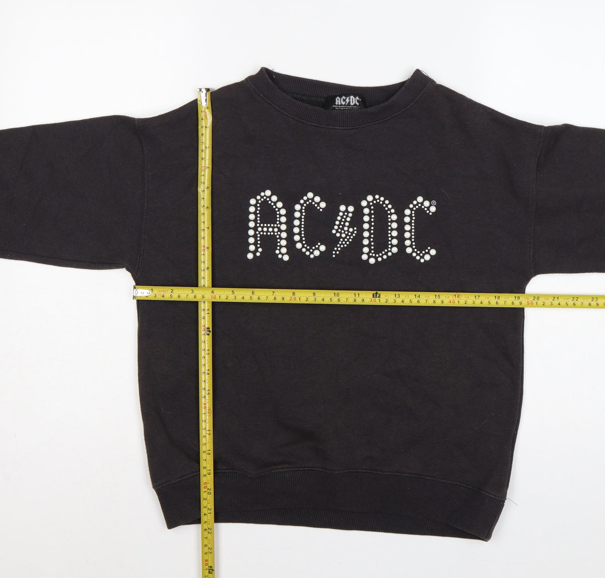 Close-up detail of AC/DC girls’ black pearl logo pullover sweatshirt 13-14 years