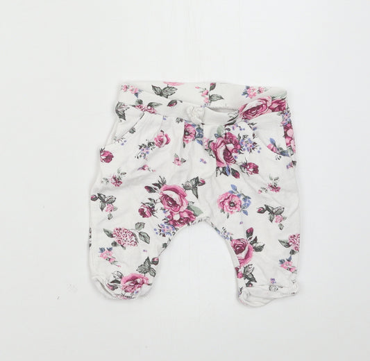 Front view of Nutmeg girls’ white floral jersey jogger trousers, size 0-3, months